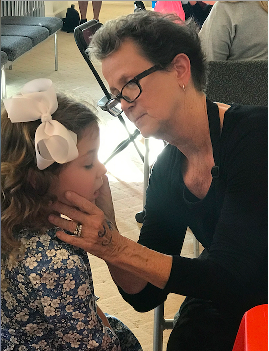 Woman face painting a small child. 